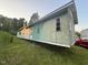 Side exterior view of a single-story home with faded green siding and overgrown grass at , Cameron, NC 28326