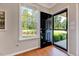 Well-lit entryway with a dark-stained door, hardwood flooring, and a view of the landscaped front yard at 1004 Sounding Ln, Durham, NC 27703