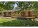 Backyard view of a cozy home with a long wood deck, brick patio, and lush landscaping at 18 Red Pine Rd, Chapel Hill, NC 27516