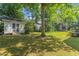 Spacious backyard featuring a green lawn, mature trees, shed and wooden deck at 208 Holly Green Ln, Holly Springs, NC 27540
