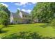 Expansive backyard with a lush green lawn, mature trees, patio, and wooden deck at 208 Holly Green Ln, Holly Springs, NC 27540