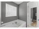 Gray bathroom featuring a tub with a glass block window and a white shower at 208 Holly Green Ln, Holly Springs, NC 27540