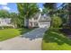 Lovely home with lush lawn, mature trees, and a long driveway leading to a two-car garage at 208 Holly Green Ln, Holly Springs, NC 27540