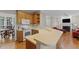 Open kitchen with countertop and wood cabinets overlooking a cozy living room area with fireplace at 208 Holly Green Ln, Holly Springs, NC 27540