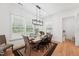 Bright dining room features hardwood floors, modern lighting, and a large window for ample natural light at 237 Emory Bluffs Dr, Holly Springs, NC 27540