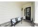 Inviting front porch with a bench, decorative pillows, and a welcoming wreath on the front door at 237 Emory Bluffs Dr, Holly Springs, NC 27540