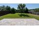Manicured backyard featuring a stone patio, lush green grass, mature trees and perimeter wood fencing at 2826 Tulip Poplar Cir, Durham, NC 27704