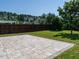 Landscaped backyard featuring a stone patio, tall wood fence, lush green grass, and mature trees at 2826 Tulip Poplar Cir, Durham, NC 27704