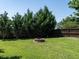 Beautiful backyard featuring a fire pit, lush green grass, and privacy trees along the fence line at 2826 Tulip Poplar Cir, Durham, NC 27704