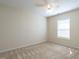 Neutral bedroom featuring beige walls, patterned carpet, a ceiling fan, and natural light from a window at 2826 Tulip Poplar Cir, Durham, NC 27704