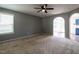 Bright living room featuring neutral carpet, gray walls, a modern ceiling fan, and an arched doorway at 2826 Tulip Poplar Cir, Durham, NC 27704