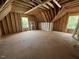 Unfinished attic space featuring exposed wood beams, rafters, and subflooring throughout at 30 Cherry Bark Dr, Youngsville, NC 27596