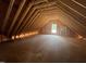 An unfinished attic with exposed wood beams, rafters, subflooring and window at 30 Cherry Bark Dr, Youngsville, NC 27596