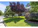Beautiful brick house featuring an expansive green lawn and mature landscaping, including a vibrant red tree at 308 Sutton Glen Dr, Apex, NC 27523