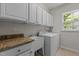 Clean laundry room with white cabinets, granite countertops, a utility sink and a modern washer and dryer at 308 Sutton Glen Dr, Apex, NC 27523