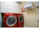 Laundry room with new, red, front-loading washer and dryer and white cabinets at 4203 Overcup Oak Ln, Cary, NC 27519