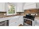 Bright kitchen featuring a brick backsplash, stainless steel appliances, white cabinets and marble counters at 625 New Road Rd, Raleigh, NC 27608