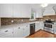 Bright kitchen featuring a brick backsplash, stainless steel appliances, and white cabinetry at 625 New Road Rd, Raleigh, NC 27608