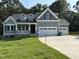 Two-story home with a two car garage, gray paint and stone accents, situated on a lawn with surrounding trees at 78 Mineral Springs Way, Benson, NC 27504