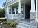 Front porch featuring stone pillars, gray siding and white railings adding curb appeal to the home at 78 Mineral Springs Way, Benson, NC 27504