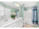 Bright bathroom with double sinks, white cabinets, large mirror, and shower-tub combo with tile surround at 78 N Porcenna Ln, Clayton, NC 27527