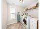 Functional laundry room with washer, dryer, storage cabinets, and a convenient ironing station at 78 N Porcenna Ln, Clayton, NC 27527