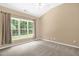 This bedroom features a large window providing ample natural light and neutral-toned carpet at 7807 Braefield Dr, Raleigh, NC 27616