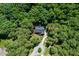 An aerial view shows a gray roofed home nestled among lush, green trees at 83 Calabria Ct, Clayton, NC 27527