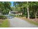 A quaint home sits surrounded by lush trees and a long gravel drive leading to a carport at 904 Lanier Farm Rd, Sanford, NC 27330