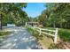 View of the home and white fence, nestled between trees, with a gravel driveway and carport at 904 Lanier Farm Rd, Sanford, NC 27330