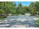 Wide shot of a gravel yard, shadowed by trees, with a carport and fenced-off section at 904 Lanier Farm Rd, Sanford, NC 27330