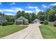 Beautiful home with a long driveway, a detached garage, green lawn, and a serene wooded backdrop at 101 Ferndale Ct, Clayton, NC 27520