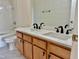 Bright bathroom features a double vanity, black hardware, quartz countertop, and a tub with shower at 1121 Brookhill Way, Cary, NC 27519