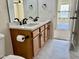 Bathroom featuring double sinks, white countertop, wood cabinets, modern black hardware, and tile floor at 1121 Brookhill Way, Cary, NC 27519