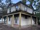 Two-story home featuring peeling paint, mature trees, and a covered front porch with columns at 12670 School House Rd, Middlesex, NC 27557