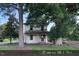 Two-story house with a covered front porch and mature trees in the front yard at 12670 School House Rd, Middlesex, NC 27557