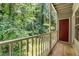 View from a balcony with a painted wood railing overlooking a lush, mature forest and a red door at 1320 Park Glen Drive Dr # 204, Raleigh, NC 27610