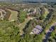 Aerial view of a lush golf course winding through trees, adjacent to outbuildings and a road at 1326 Fairview Club Dr, Wake Forest, NC 27587