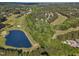 Aerial view of a picturesque golf course with a pond, lush greenery, and surrounding trees in a residential community at 1326 Fairview Club Dr, Wake Forest, NC 27587