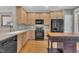 Bright kitchen featuring wooden cabinets and black appliances with wood floor at 1326 Fairview Club Dr, Wake Forest, NC 27587