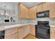 Bright kitchen featuring wooden cabinets and black appliances with wood floor at 1326 Fairview Club Dr, Wake Forest, NC 27587