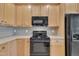 Bright kitchen featuring wooden cabinets and black appliances with wood floor at 1326 Fairview Club Dr, Wake Forest, NC 27587