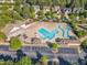 Aerial view of a community pool with a spacious deck and lounge area surrounded by trees and parking at 1326 Fairview Club Dr, Wake Forest, NC 27587