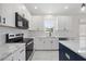 Modern kitchen with marble countertops, stainless appliances, a navy island, and white cabinetry at 1805 Abby Knoll Dr, Apex, NC 27502