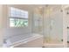 Bright bathroom featuring a soaking tub under a window and a glass shower with bench at 1830 Wilshire Ave, Raleigh, NC 27608