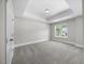 Bright bedroom features tray ceiling, window, carpet floors, and neutral paint at 2223 Copper Pond Way, Fuquay Varina, NC 27526