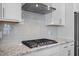 Close up on a gas cooktop, granite countertop, stainless steel vent hood, and subway tile backsplash at 2223 Copper Pond Way, Fuquay Varina, NC 27526