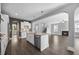Open kitchen with island, stainless steel appliances and hardwood floors leads to living room with fireplace at 2223 Copper Pond Way, Fuquay Varina, NC 27526