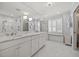 Bright, white bathroom with marble countertops, chandeliers, a glass shower, and storage bench at 227 W Drewry Ln, Raleigh, NC 27609