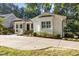 Charming home with a white brick facade, black shutters, and a spacious driveway surrounded by lush greenery at 227 W Drewry Ln, Raleigh, NC 27609